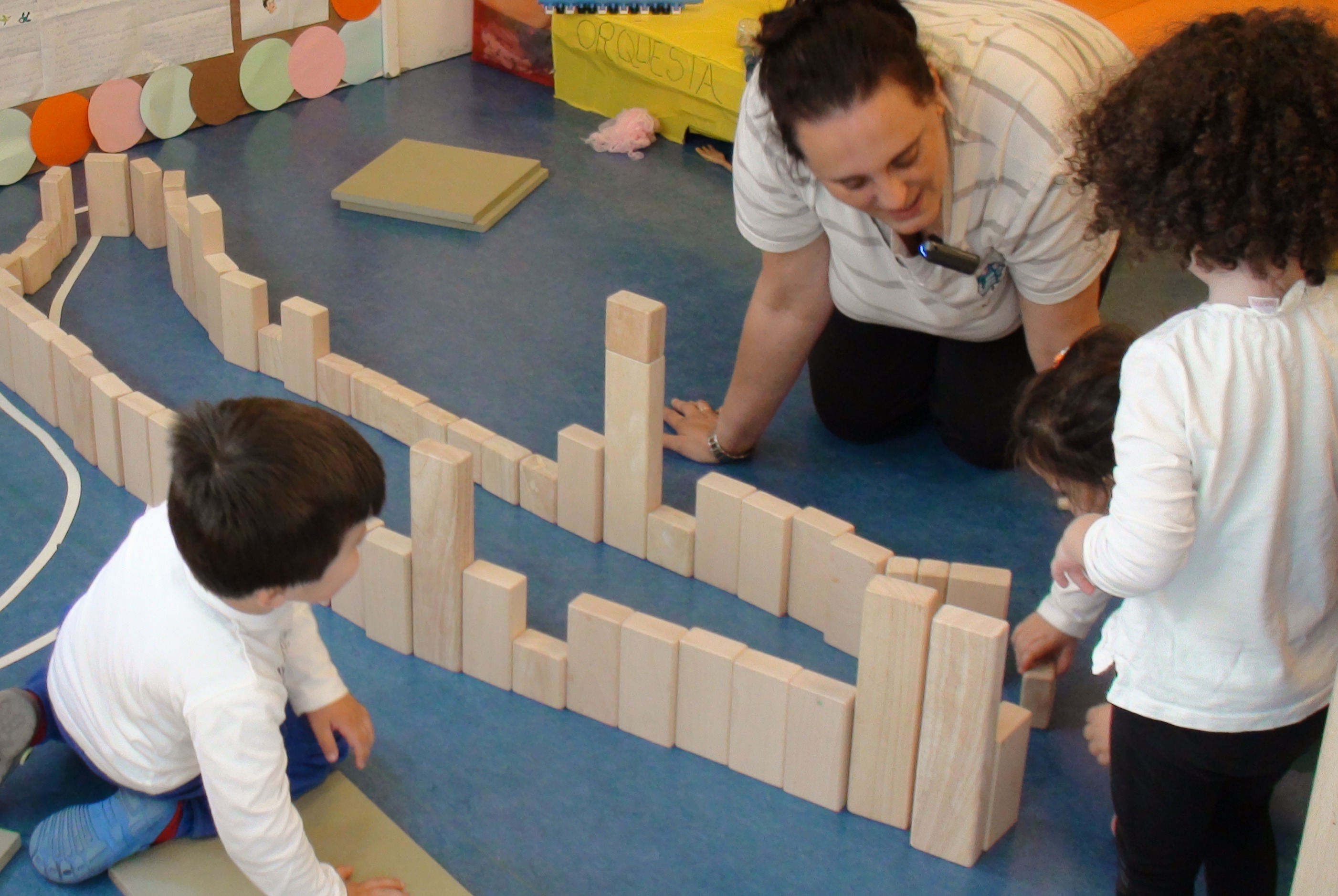 Varios alumnos construyendo con bloques mientras la maestra observa