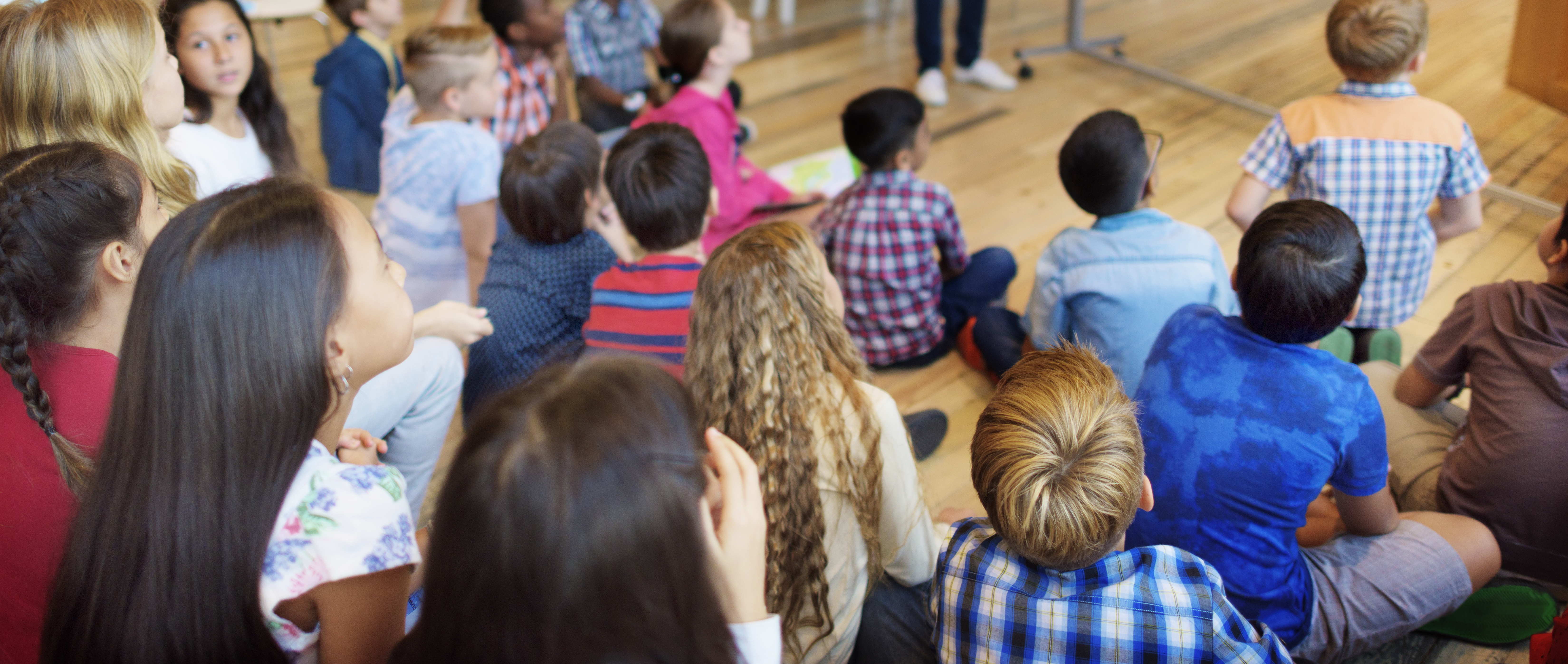 Los alumnos de una clase sentados en semicírculo escuchando al docente