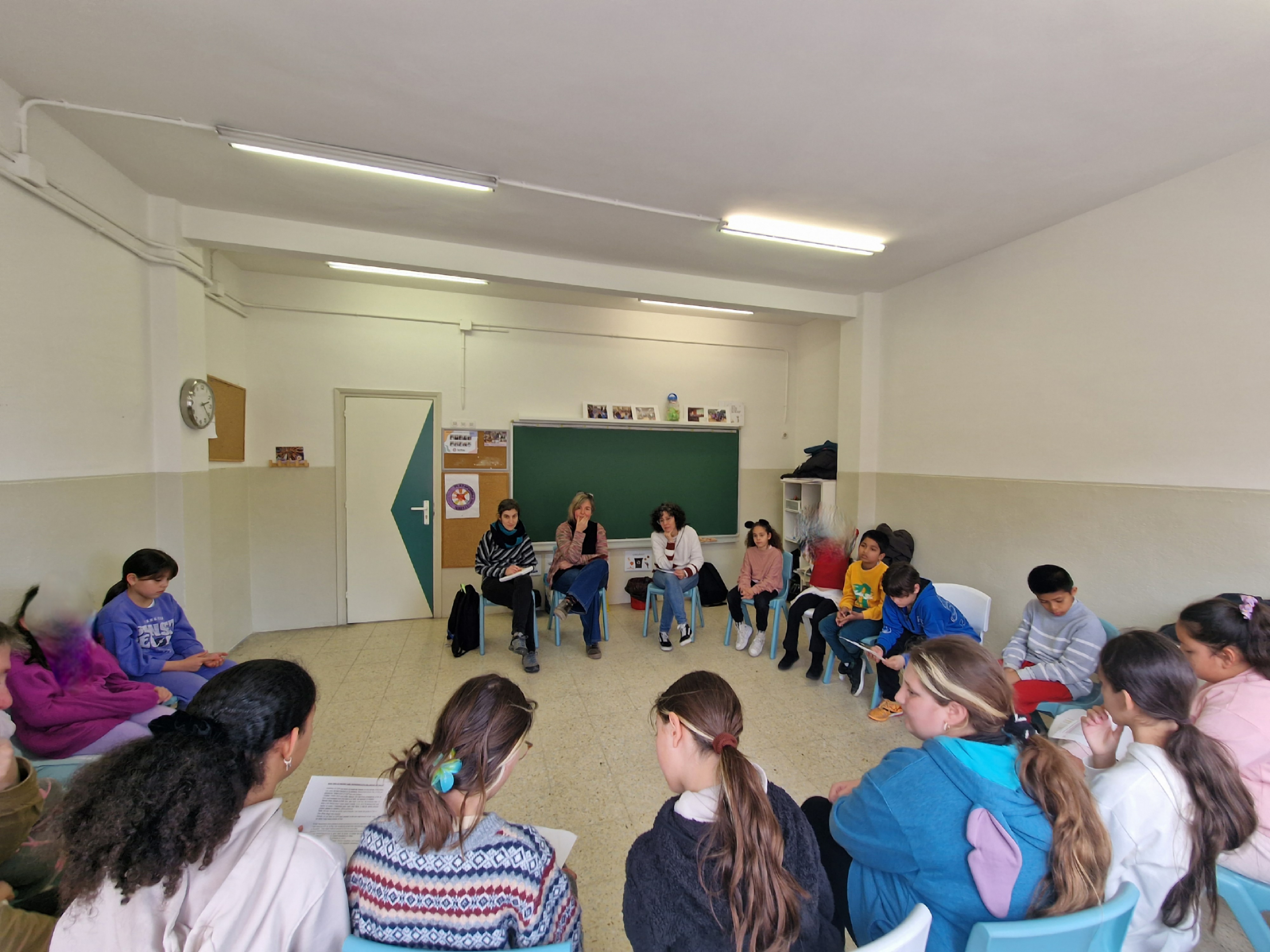 Alumnos y docentes sentados en clase en círculo